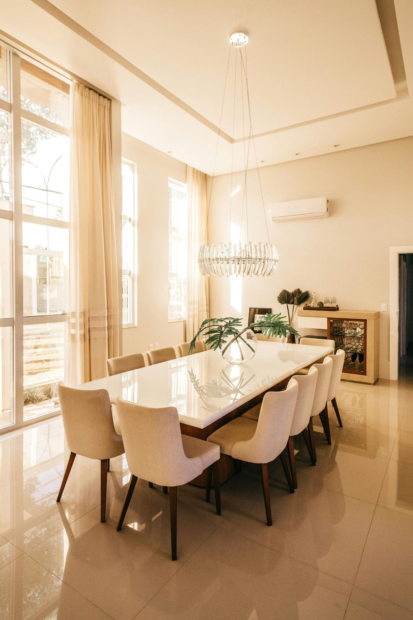 A dining room with a long table and chairs and a piano.